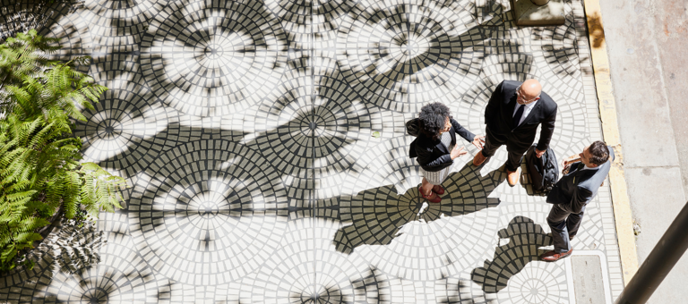 Three business people having a conversation on tree lined sidewalk