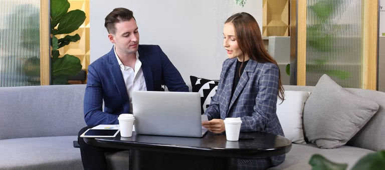 Two people looking at a laptop in a relaxed office environment