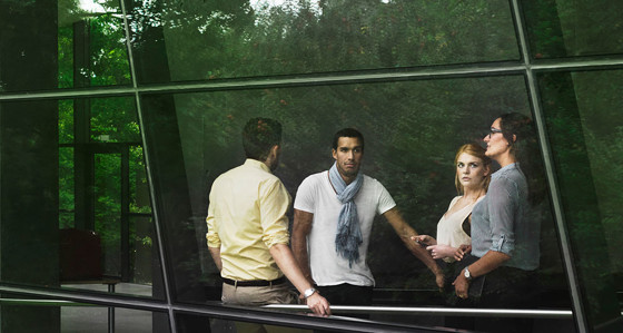 A group of people can be seen through a window with reflections of plants around them