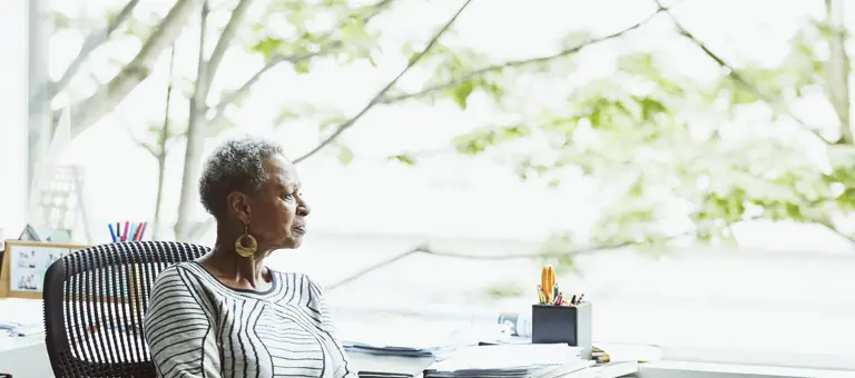 A woman looking out of her office window towards trees