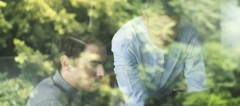 Two people looking at a hidden-from-view screen with trees in the background