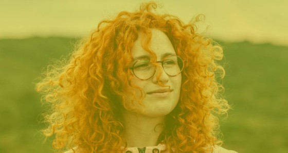 A woman's face with a hillside in the background