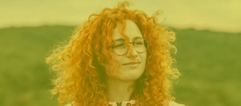 A woman's face with a hillside in the background