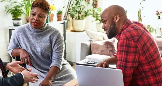 A couple in their home in discussion with a business advisor