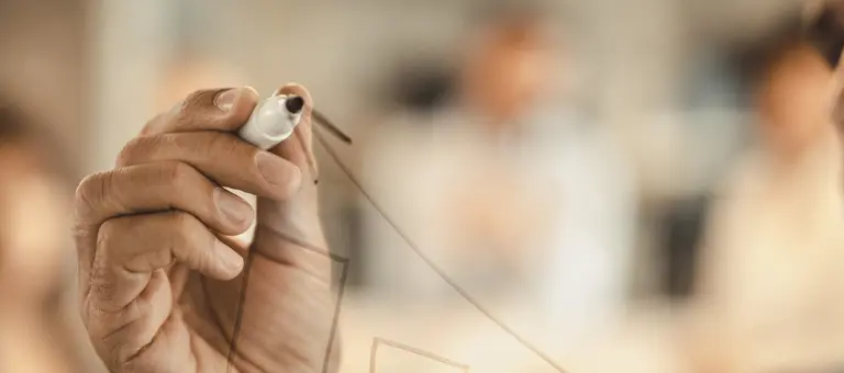A man drawing a graph on a transparent wall