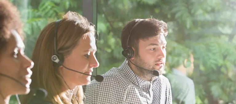Three people wearing headsets working in a call centre