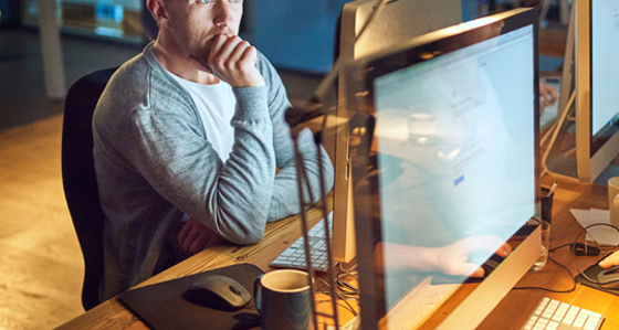 A man deep in thought while looking at his computer