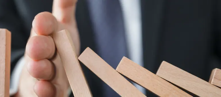 A hand stopping dominos from falling over