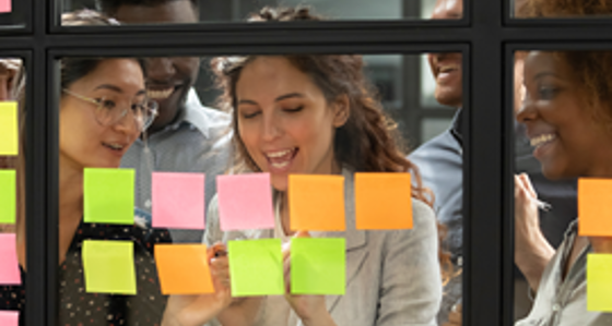 Four people looking at post its on a glass interior window
