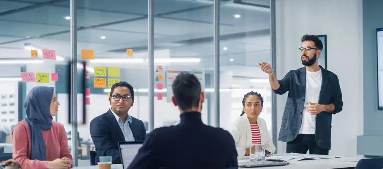 A meeting with a man standing up giving a presentation
