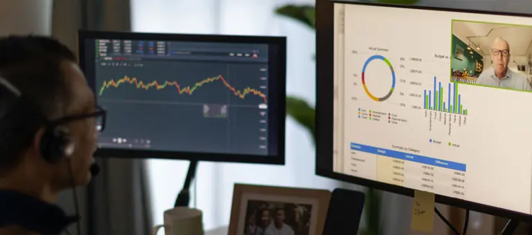 A man with a headset on an internet call looking at two screens