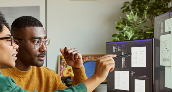 A man and a woman discussing data on a computer screen