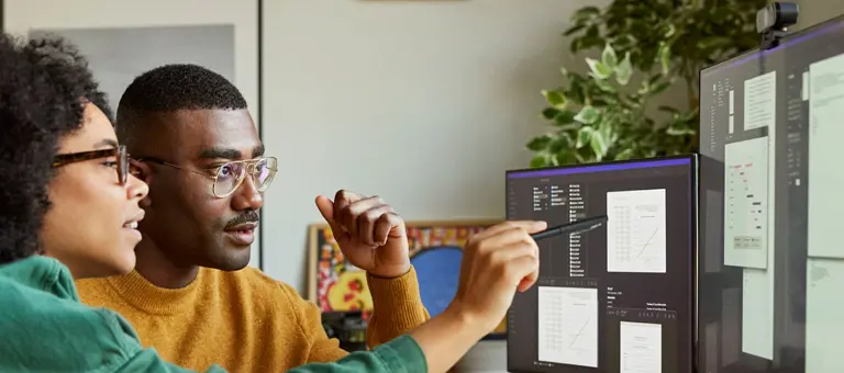 A man and a woman discussing data on a computer screen