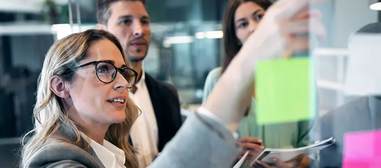 A woman sticking post-it notes on a transparent wall