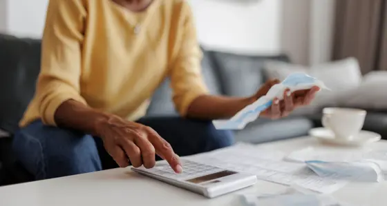Woman using a calculator while looking at her bills