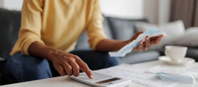 Woman using a calculator while looking at her bills