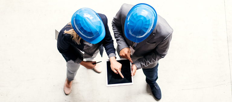 2 people in hard hats holding tablet