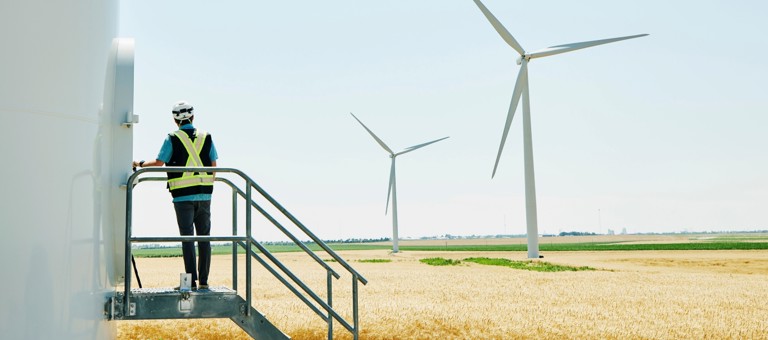 A man in a hard hat about to enter a wind turbine