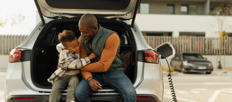 A father and his son playing together while their electric car is charging