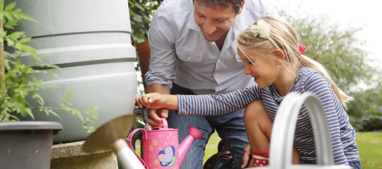 A father and his daughter filling up a watering can