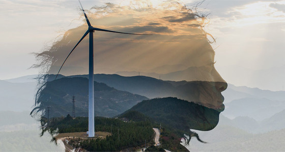 The outline of a woman's head superimposed over mountains and a wind turbine