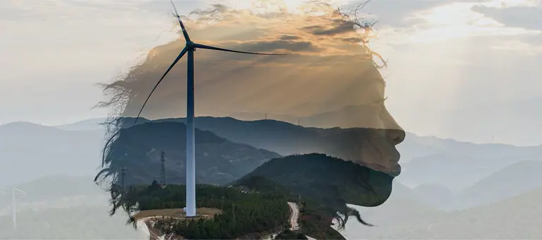 The outline of a woman's head superimposed over mountains and a wind turbine