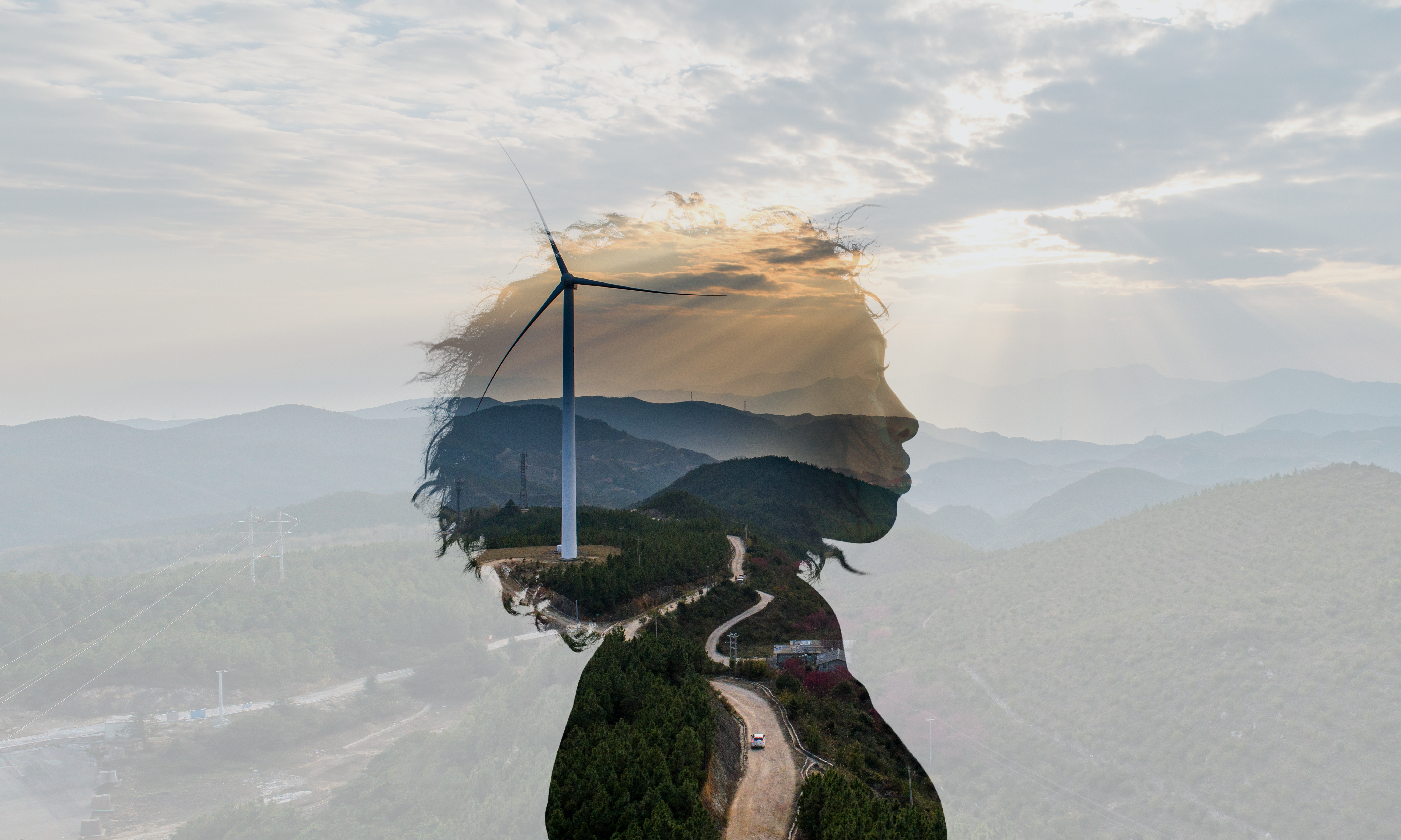 The outline of a woman's head superimposed over mountains and a wind turbine