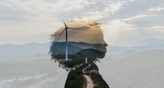 The outline of a woman's head superimposed over mountains and a wind turbine