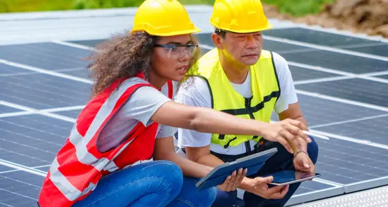 Two engineers analysing data while working with solar panels on a roof