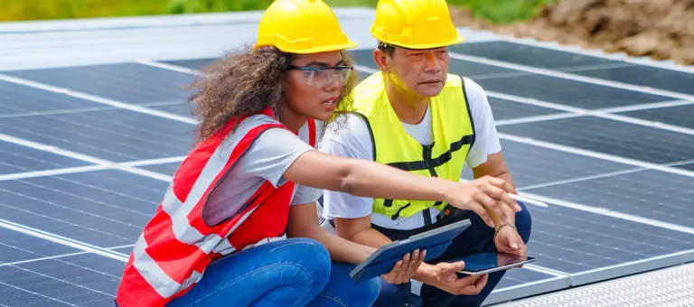 Two engineers analysing data while working with solar panels on a roof