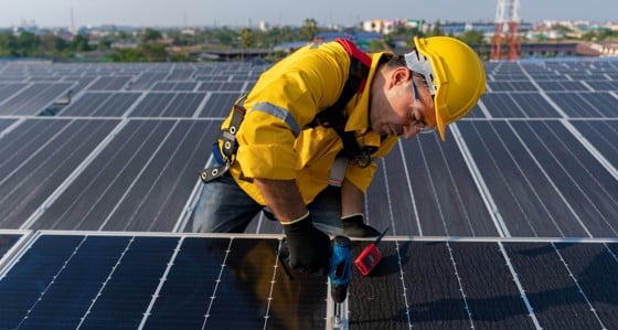 A man in hard hat working on panels at a solar farm