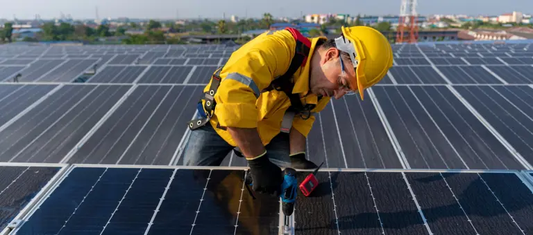 A man in hard hat working on panels at a solar farm