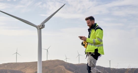 A man looking at his phone at a windfarm