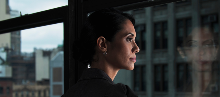 Woman looking over city, reflected in window