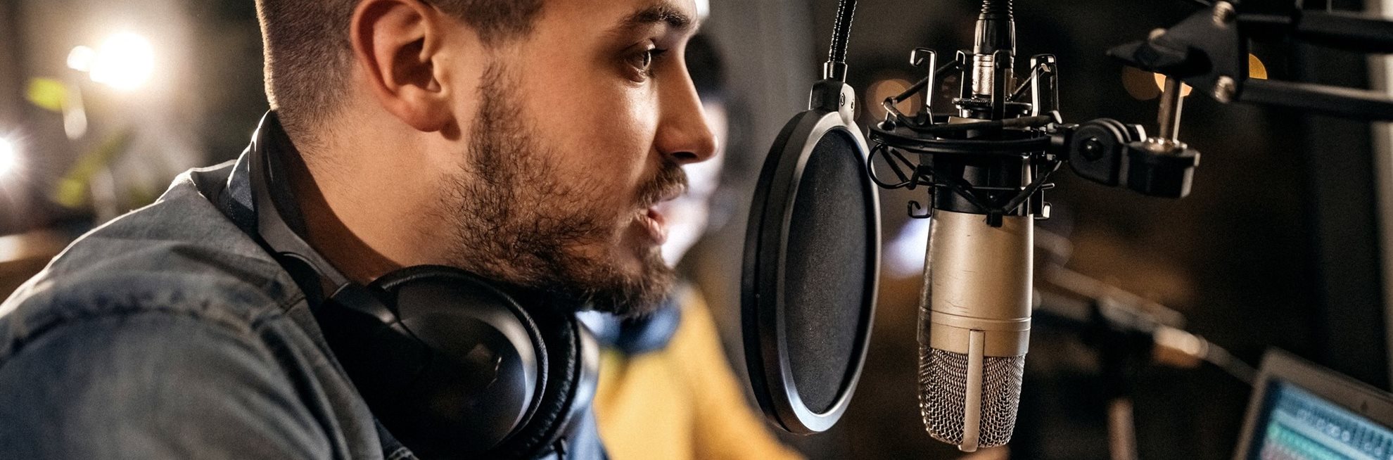 A man wearing headphones speaking into a microphone to record a podcast