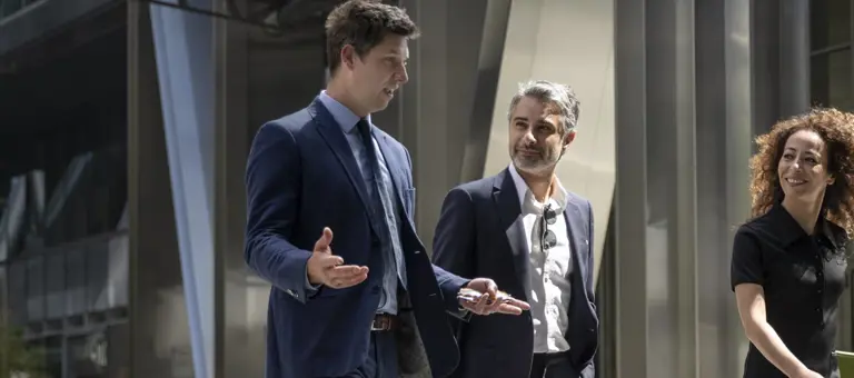 Three professionals in conversation outside an office building