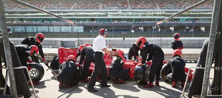 Pit crew replacing tires on race car