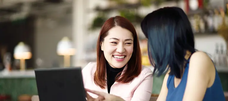 Two women talking in front of a laptop