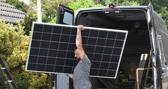 A man taking a solar panel out of a van