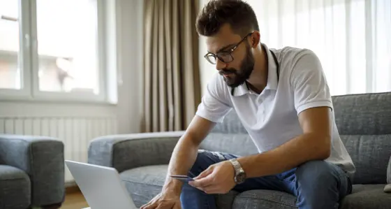 Man sitting on a sofa and making a payment on his laptop