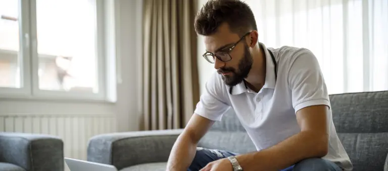 Man sitting on a sofa and making a payment on his laptop