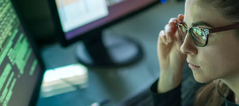 A woman with glasses looking at a computer screen