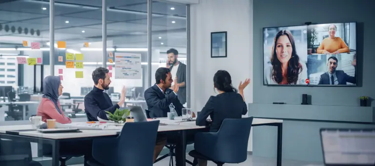 Four people in an office having a virtual meeting with three colleagues