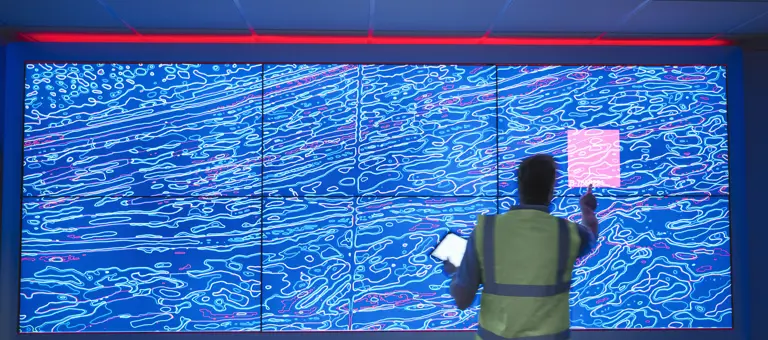 A man pressing a large interactive screen