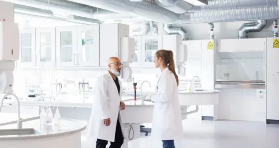 Two scientists in conversation, standing in laboratory