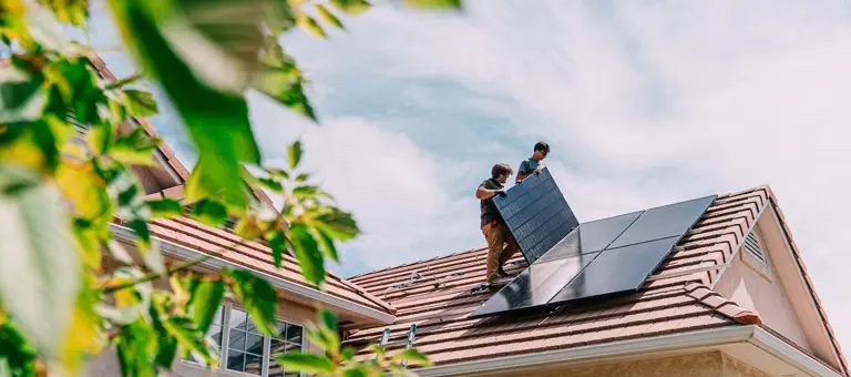 men installing solar panels on the roof of a home