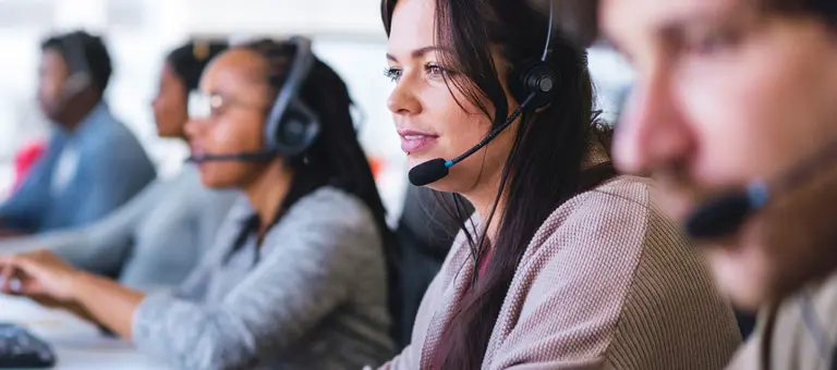 Call centre staff wearing headsets in front of their computers