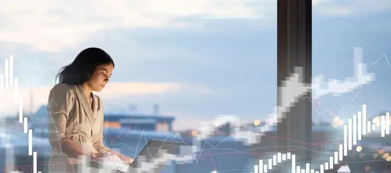 Financial specialist working on laptop with city skyline behind her and graphs surrounding her