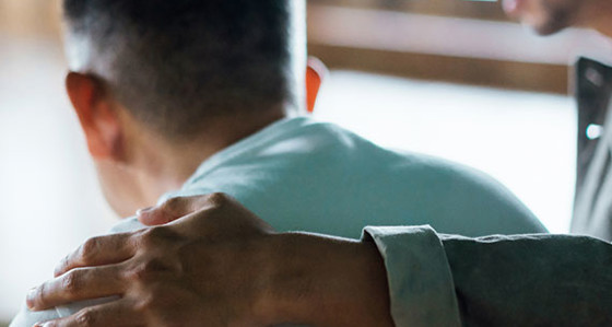 A man standing with his arm around someone comforting them