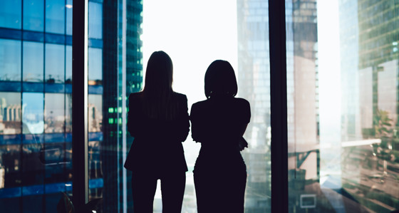 Two women looking out a window at high rise buildings